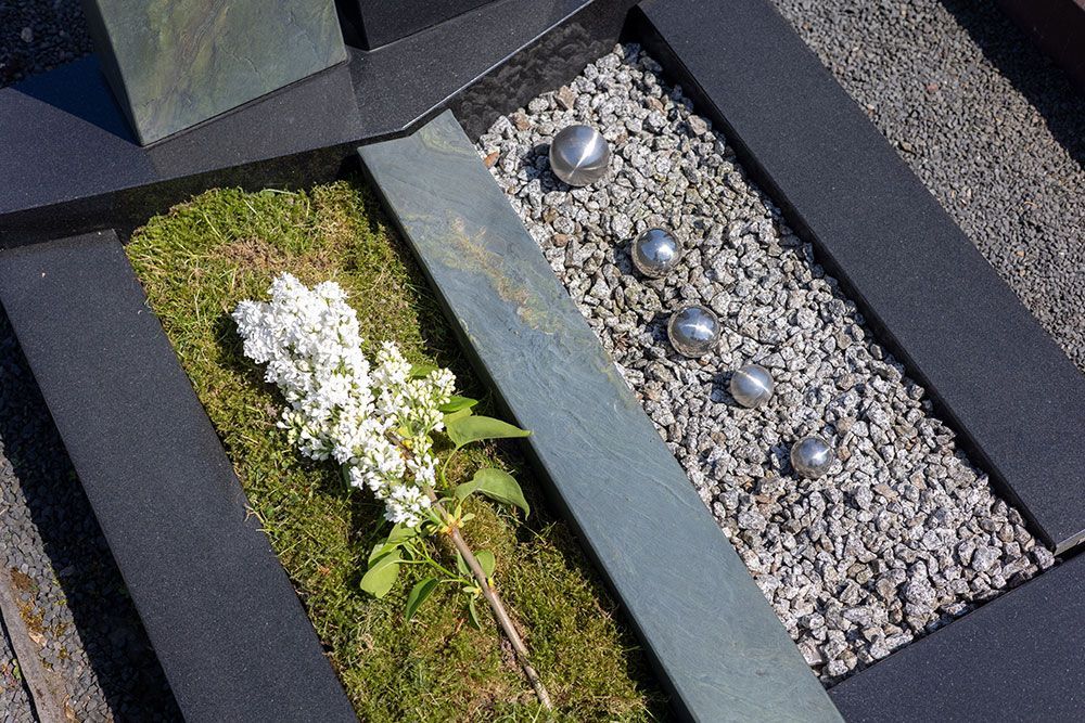 Ein Grab mit einer Blume und Kies darin