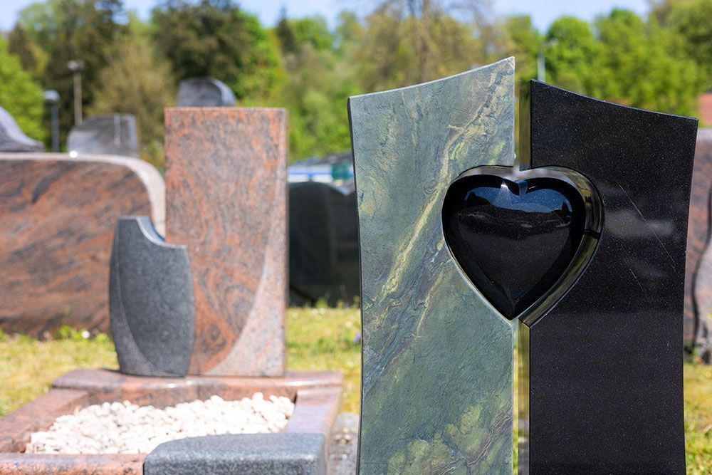 Ein Grabstein mit einem Herz in der Mitte auf einem Friedhof.