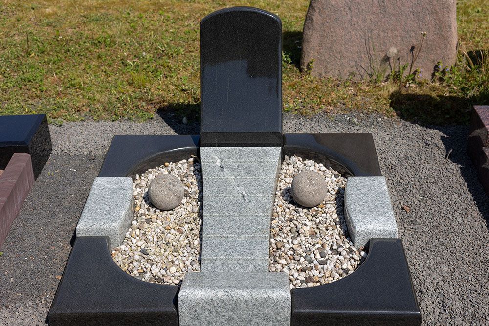 Ein schwarz-grauer Grabstein mit zwei Steinen darin