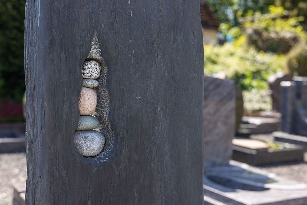 Ein Grabstein mit eingemeißelten Steinen auf einem Friedhof.