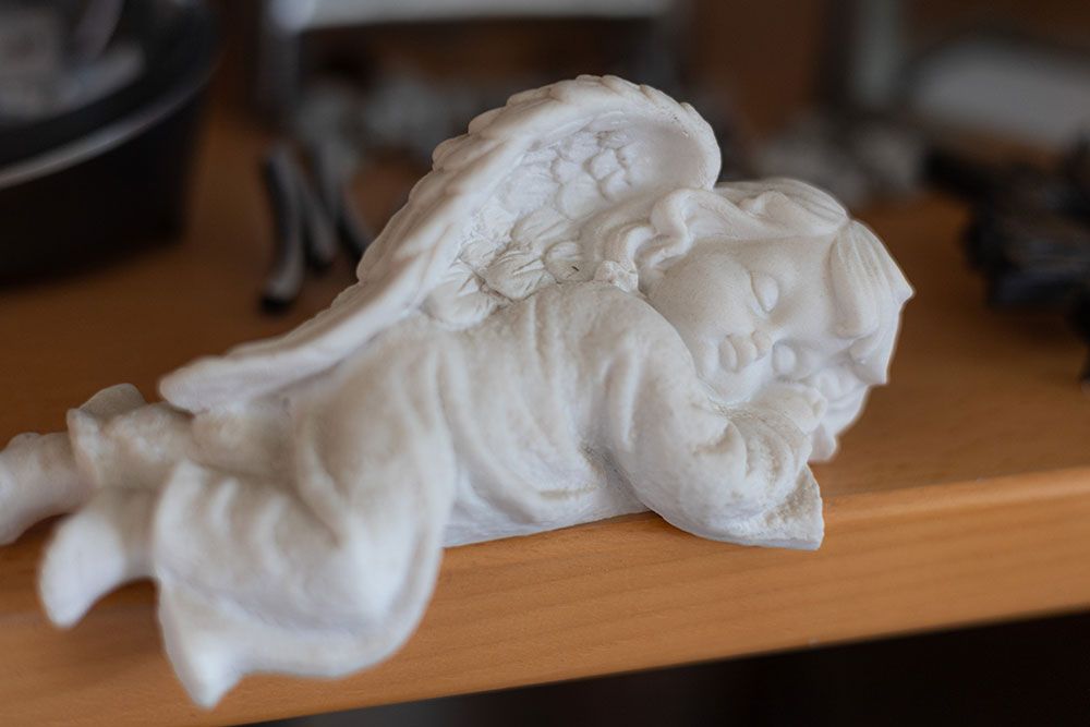 Auf einem Holztisch liegt eine weiße Engelsstatue.