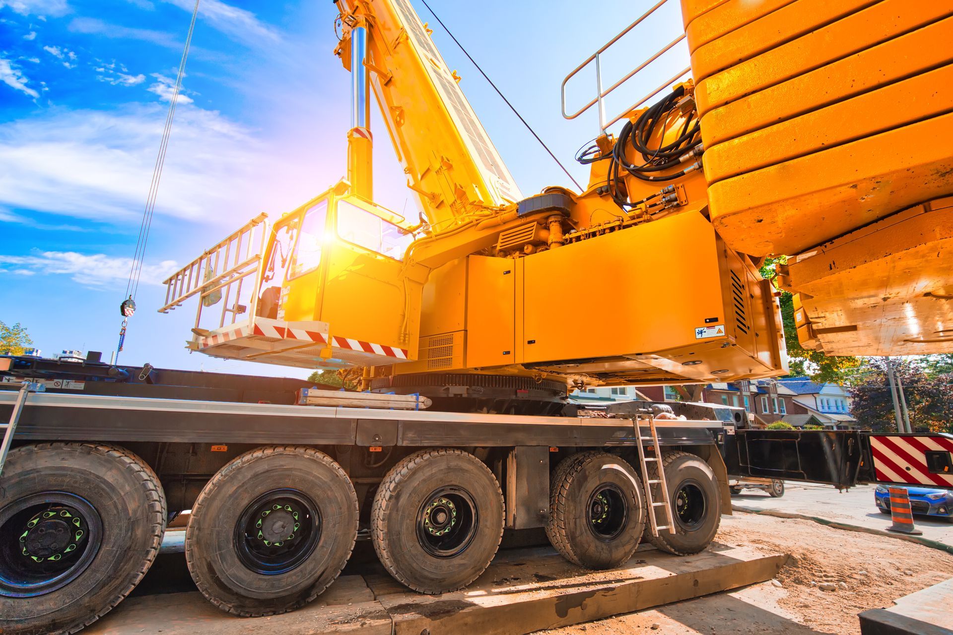 Une grande grue mobile jaune est stationnée sur un chantier de construction sous un ciel d'un bleu éclatant.