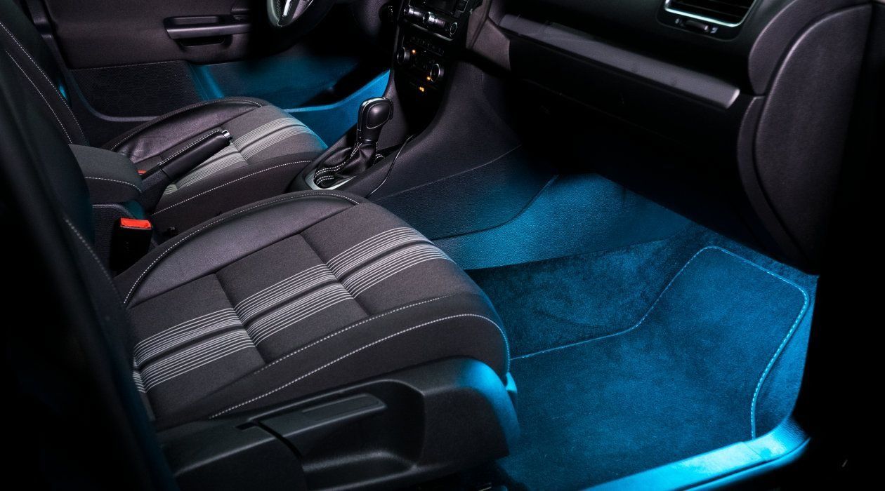 El interior de un coche con luces azules en el suelo.