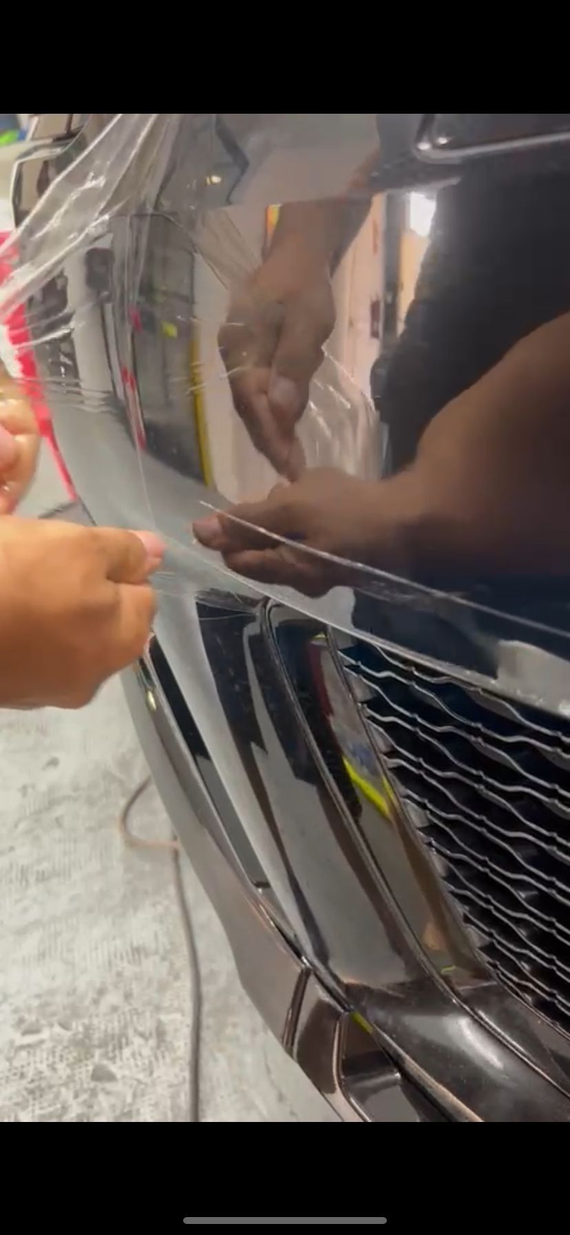 Una persona está envolviendo un automóvil con una envoltura de plástico transparente.