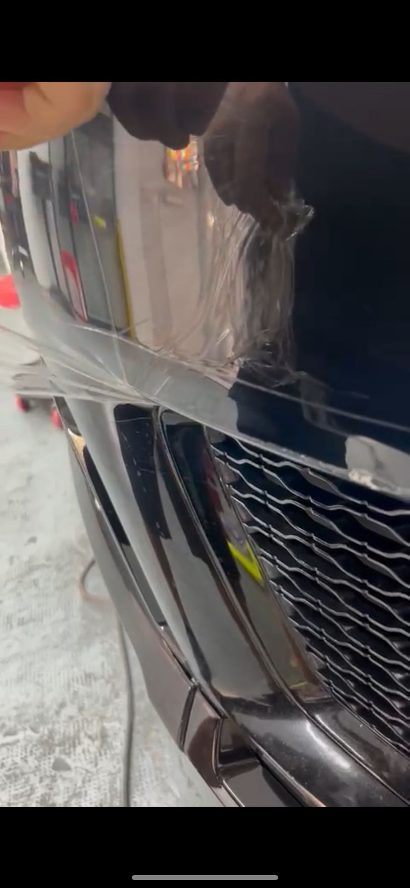 Una persona sostiene un trozo de plástico en la parte delantera de un coche.