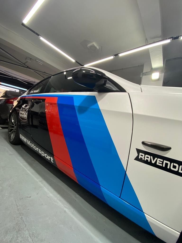 Un coche con rayas rojas, azules y blancas en los laterales está aparcado en un garaje.
