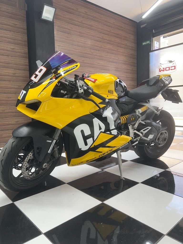 Una motocicleta amarilla y negra está estacionada sobre un piso a cuadros.