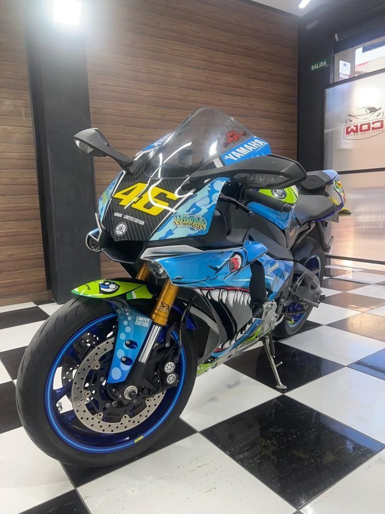 Una motocicleta azul y negra está estacionada sobre un piso a cuadros en un garaje.