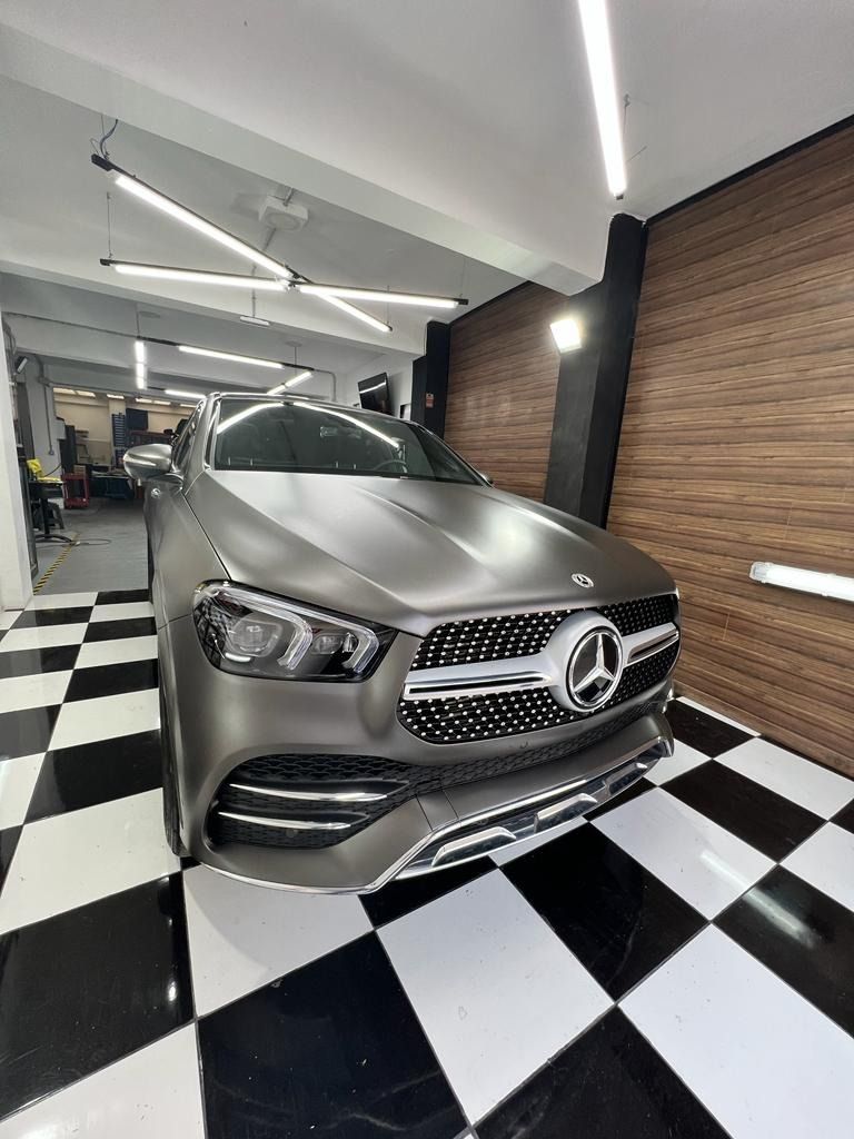 Un Mercedes Benz está estacionado en un garaje con suelo cuadriculado.