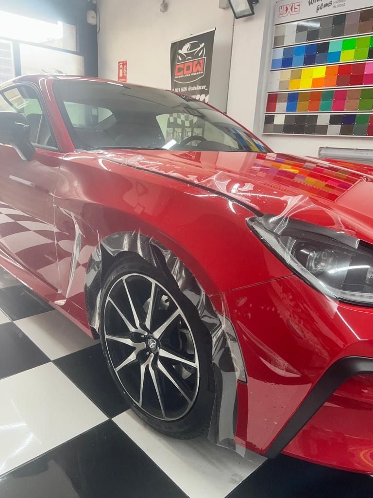Un coche rojo está aparcado sobre un suelo cuadriculado en un garaje.