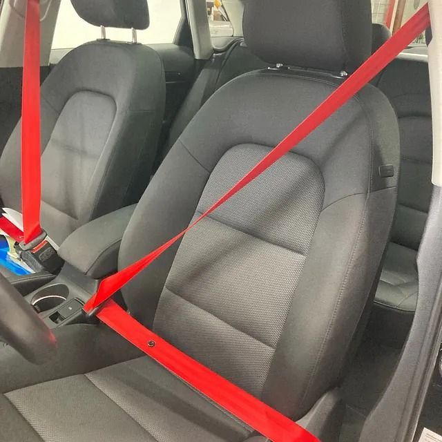 Un asiento de coche con un cinturón rojo.