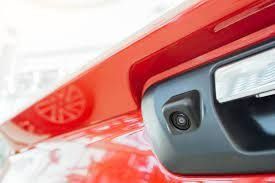 Un primer plano de una cámara de visión trasera en la parte trasera de un automóvil rojo.