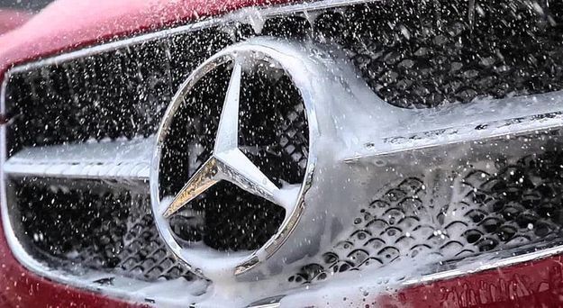 Un primer plano del logotipo de Mercedes en el frente de un automóvil rojo.