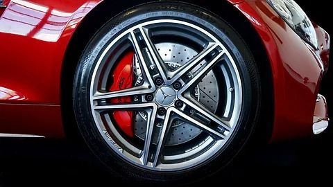 Un primer plano de una rueda de un coche deportivo rojo con una pinza de freno roja.