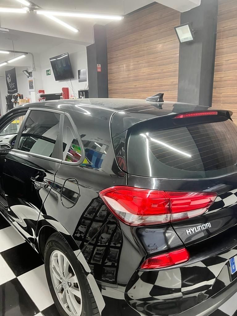 Un coche negro está aparcado en un garaje con suelo cuadriculado.