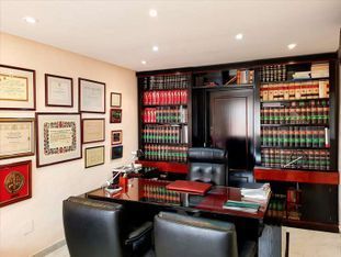 Una oficina de abogados con un escritorio, sillas y estantes llenos de libros.