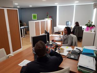 Un grupo de personas están sentadas en escritorios en una oficina trabajando con computadoras.