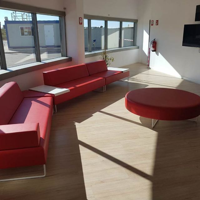 Una sala de estar con dos sofás rojos y una otomana redonda.