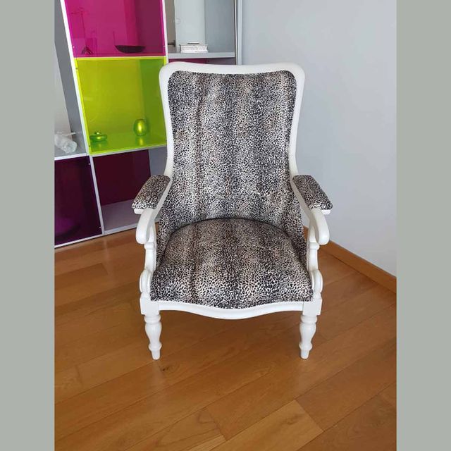 Una silla con un cojín con estampado de leopardo está sobre un suelo de madera.