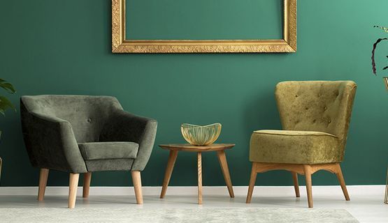 Dos sillas y una mesa en una sala de estar con paredes verdes.