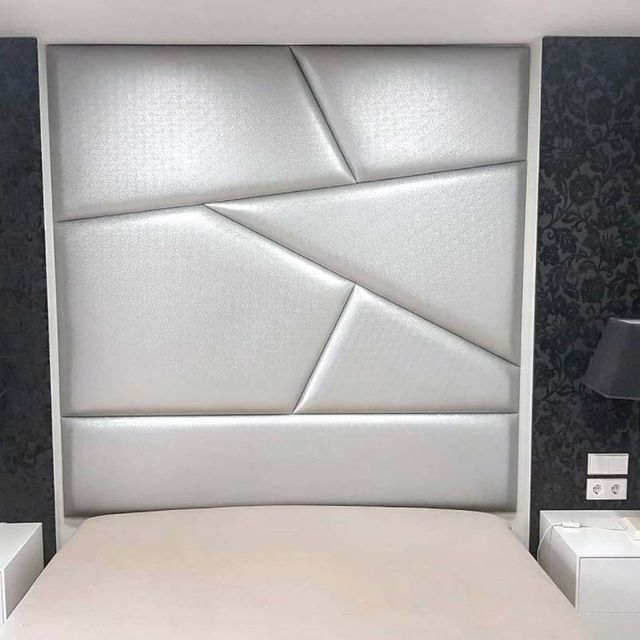 Una cama con cabecero blanco y dos mesitas de noche en un dormitorio.