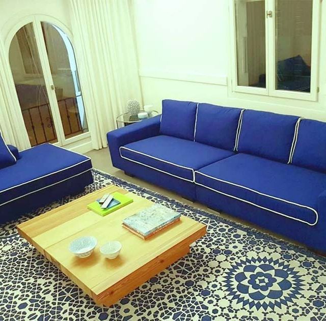Una sala de estar con un sofá azul y una mesa de centro de madera.