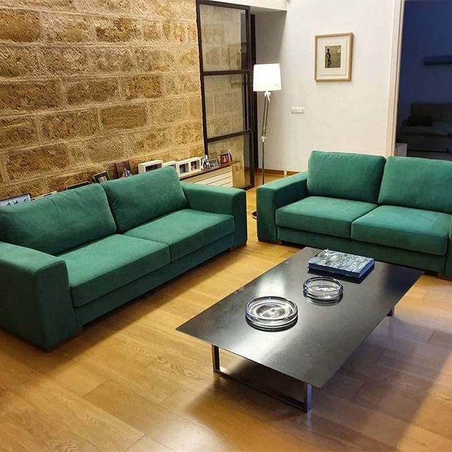 Una sala de estar con dos sofás verdes y una mesa de café.