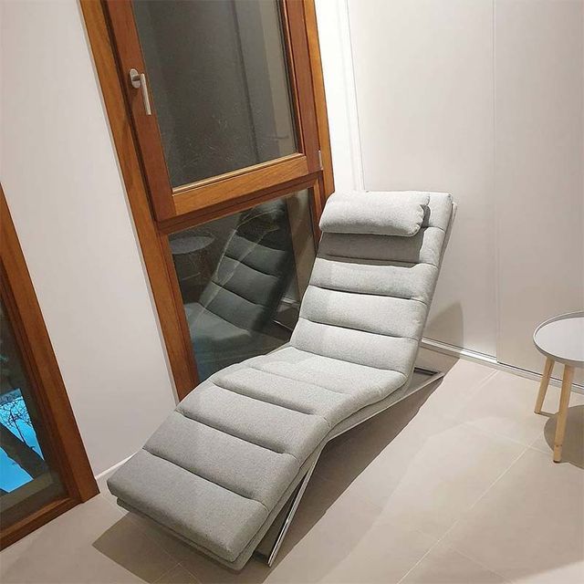 Un sillón está sentado en una habitación al lado de una ventana.