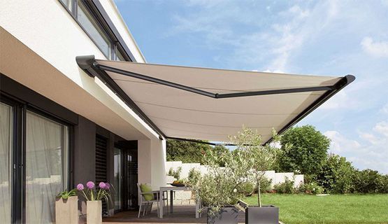 Una casa con un gran toldo sobre un patio con mesa y sillas.