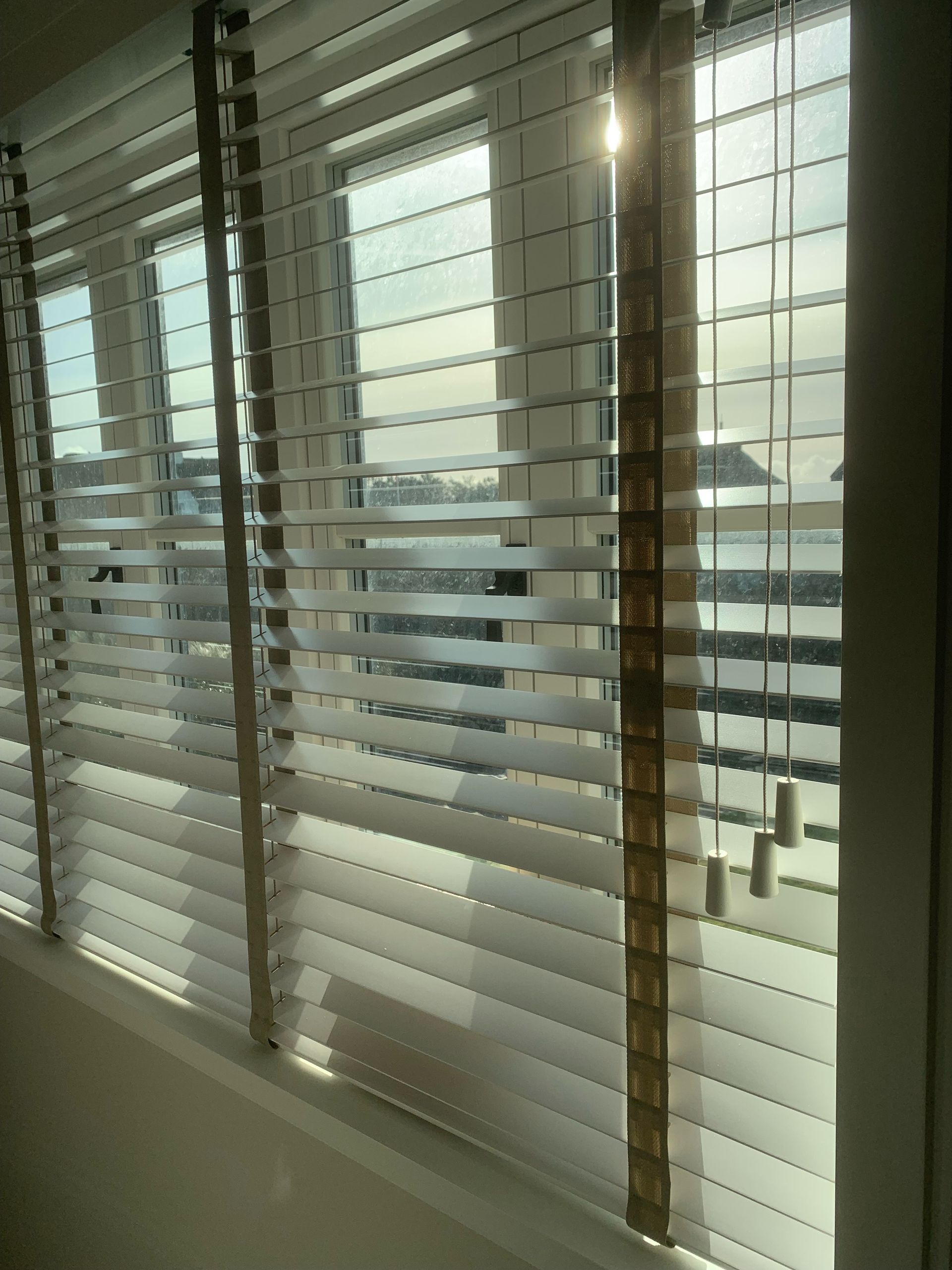 Blick durch teilweise geöffnete Jalousien; Sonnenlicht strömt herein.