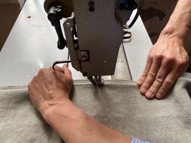 Ein minimalistischer Wintergarten mit Betonwänden, Jalousien, einem hölzernen Schaukelstuhl und einem kleinen Beistelltisch