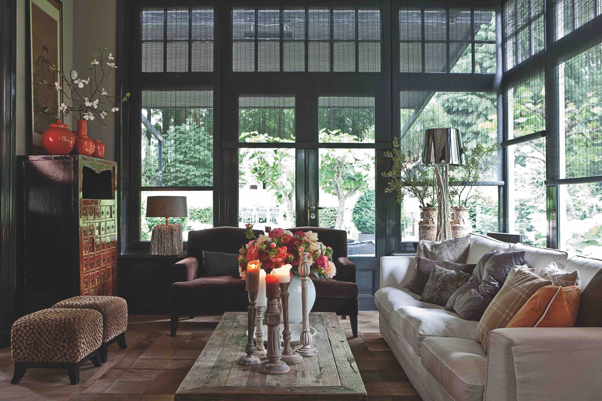 Wohnzimmer mit dunkel umrandeten Fenstern, Sofas, Couchtisch und Blick ins Grüne.