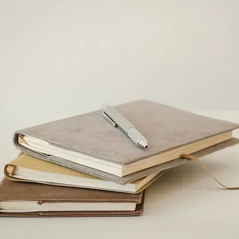 Un bolígrafo está encima de una pila de cuadernos.