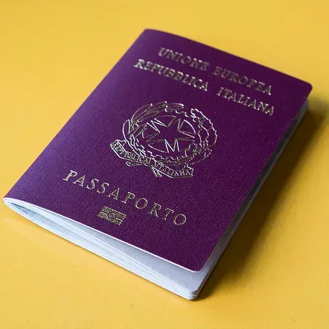 Un pasaporte morado está sobre una superficie amarilla