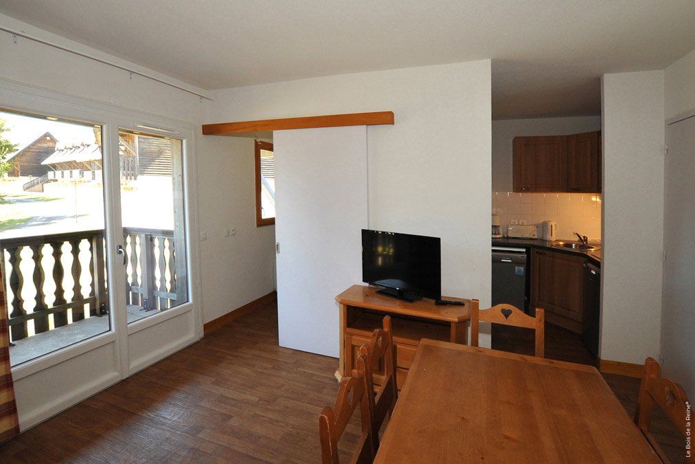 Pièce de vie avec baie vitre, table et télévision