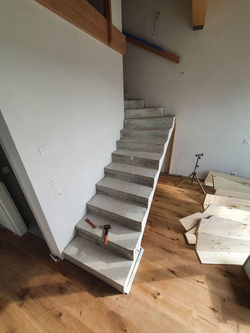 Un escalier est en cours de construction dans une pièce avec parquet.