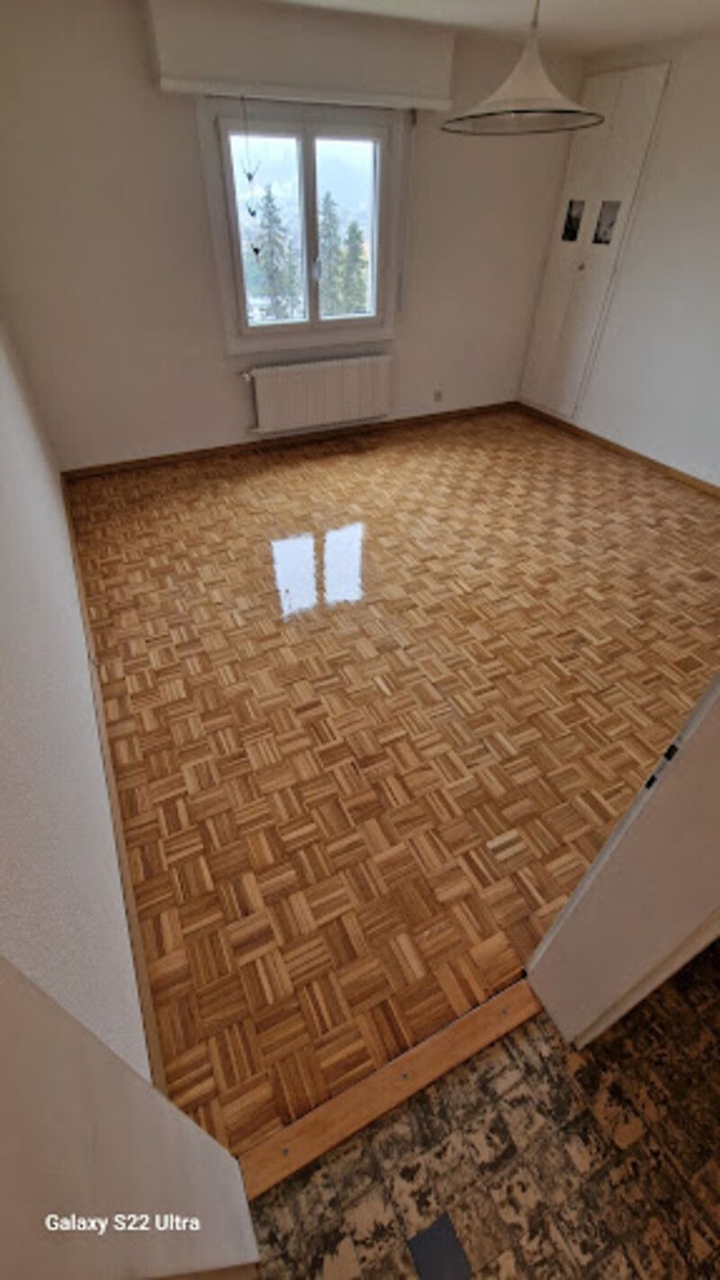 Une pièce vide avec un parquet et une fenêtre.