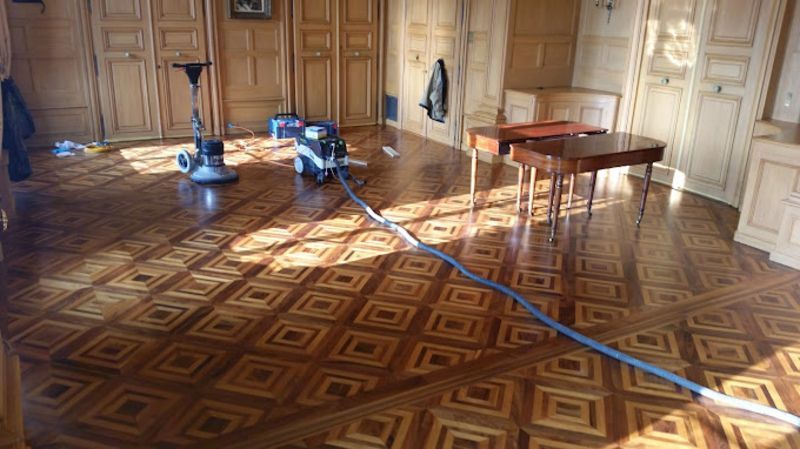 Un aspirateur est posé sur un parquet dans une pièce.