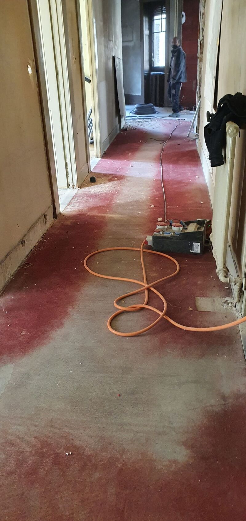 Un long couloir avec un aspirateur posé par terre.