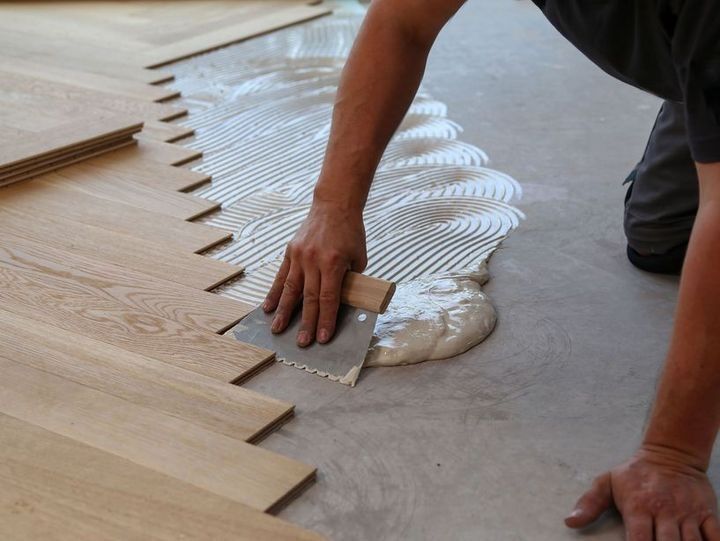 Une personne applique de la colle sur un parquet