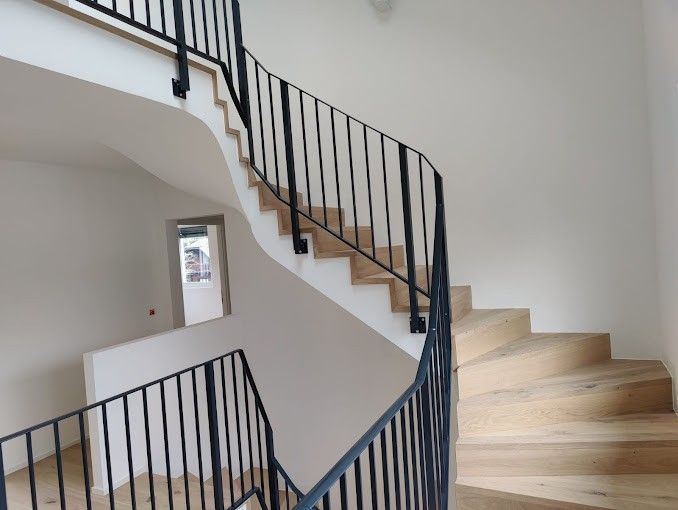 Un escalier avec une rampe en métal et des marches en parquet bois