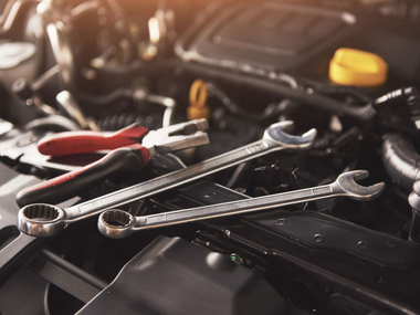 Outils de garagiste posés sur le moteur d'une voiture au capot ouvert.