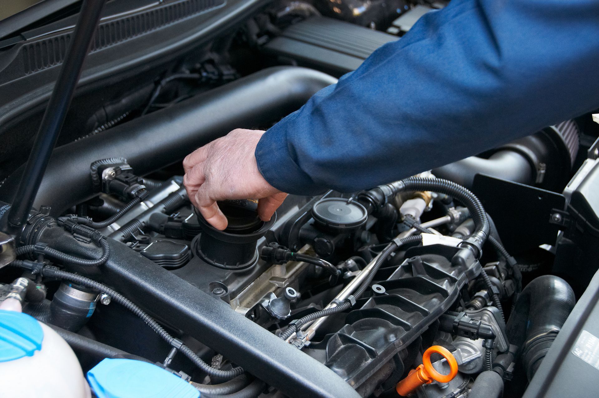 Main d'un mécanicien travaillant sur un moteur de voiture sous le capot.