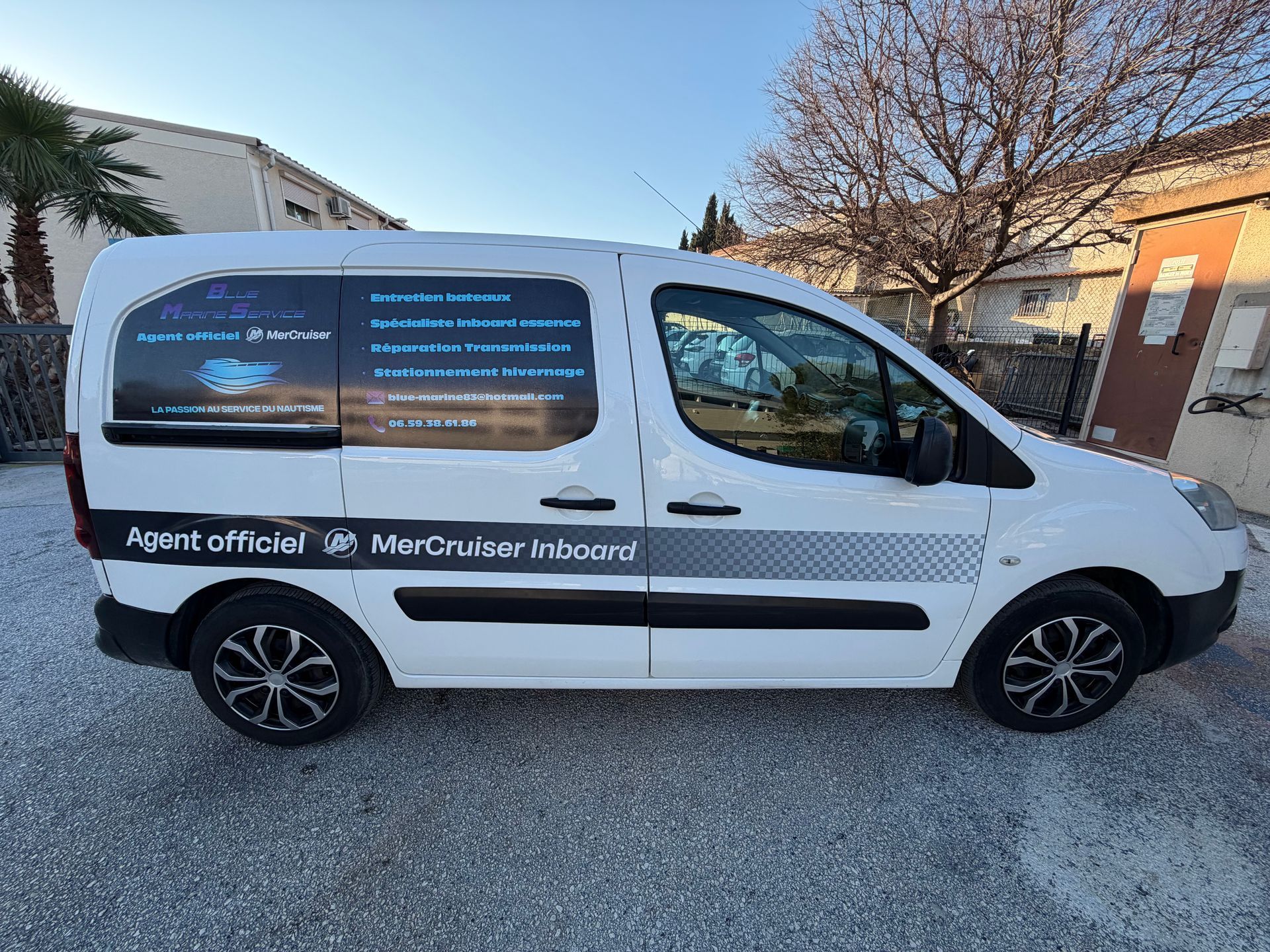 Camionnette blanche avec le logo de l'entreprise garée sur du gravier.