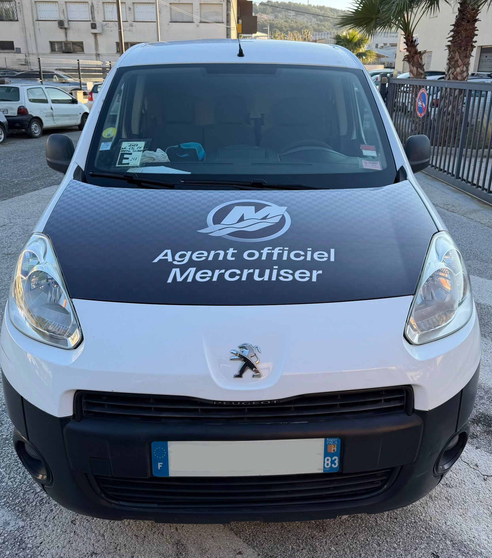 Fourgonnette Peugeot blanche et noire avec logo « Agent officiel Mercruiser ». Vue de face, plaque d'immatriculation visible.
