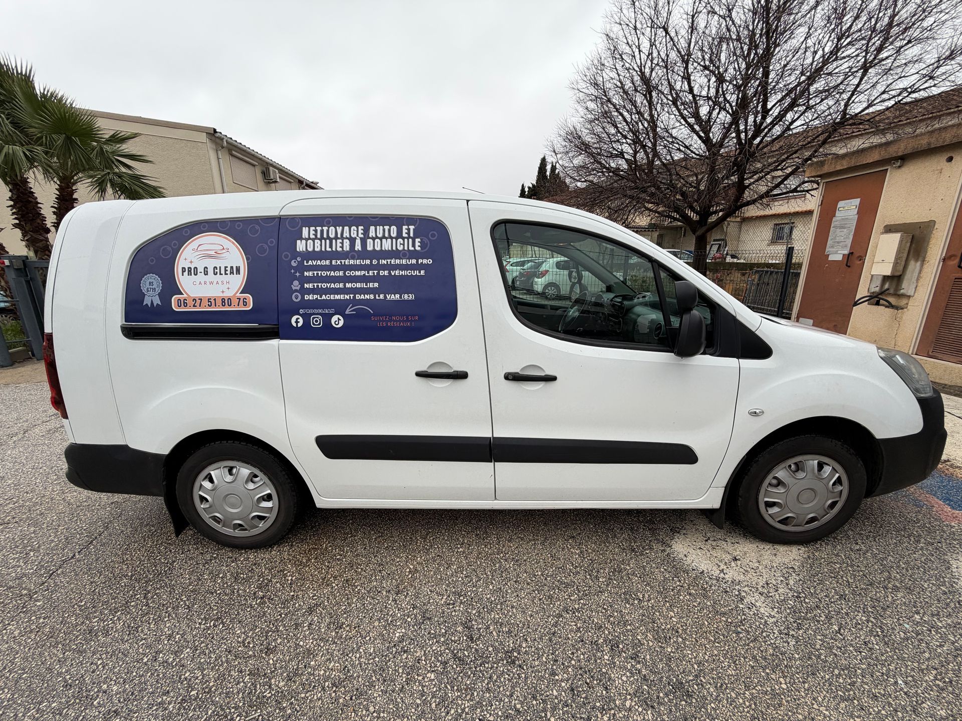 Camionnette commerciale blanche avec publicité, stationnée à l'extérieur.