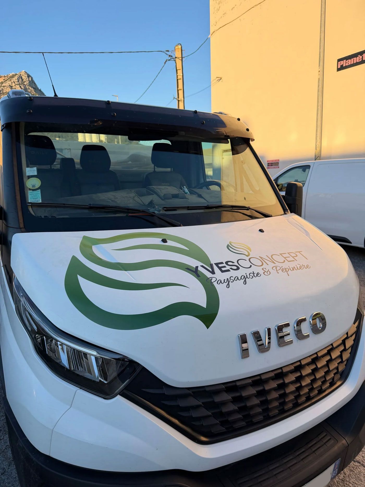 Fourgon Iveco blanc avec un covering sur le capot, logo + nom de l'enseigne