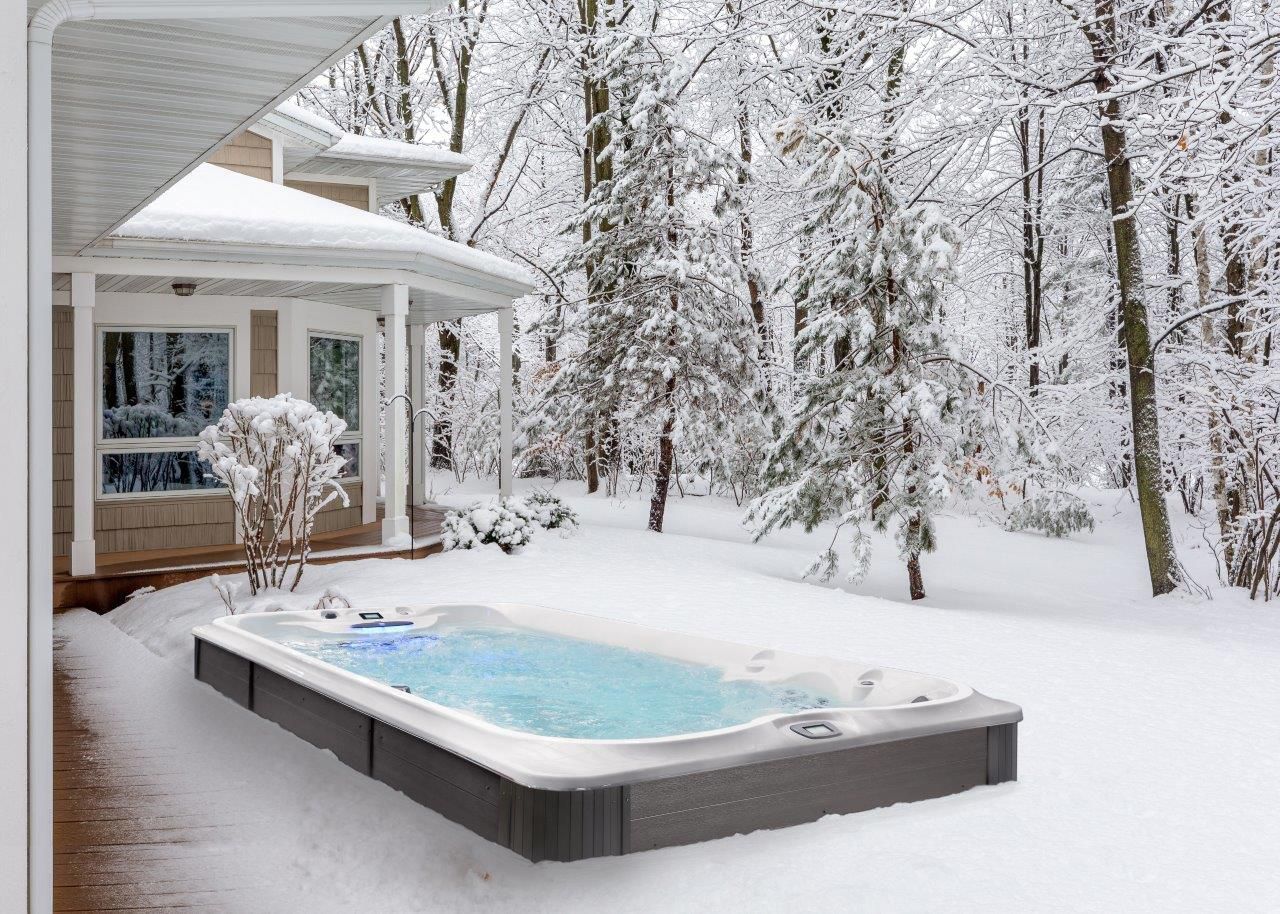 Spa de nage à l'extérieur d'une maison dans une forêt enneigée.