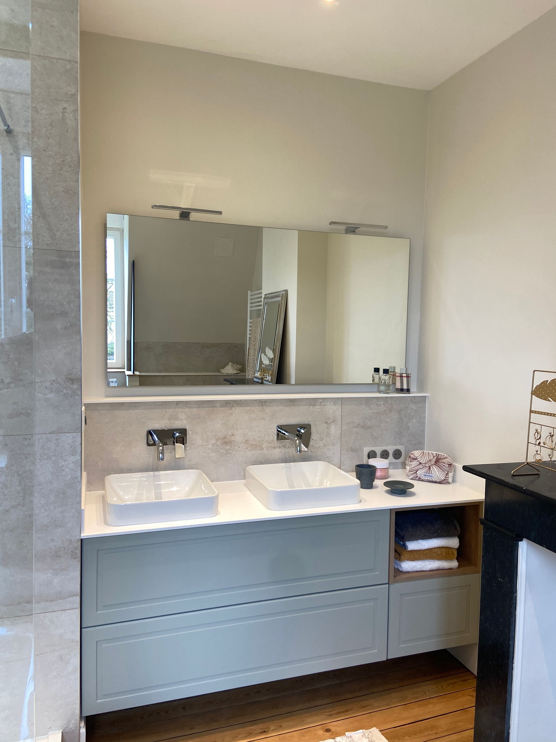 Salle de bains aux tons gris et blancs ; double vasque, grand miroir et luminaires.
