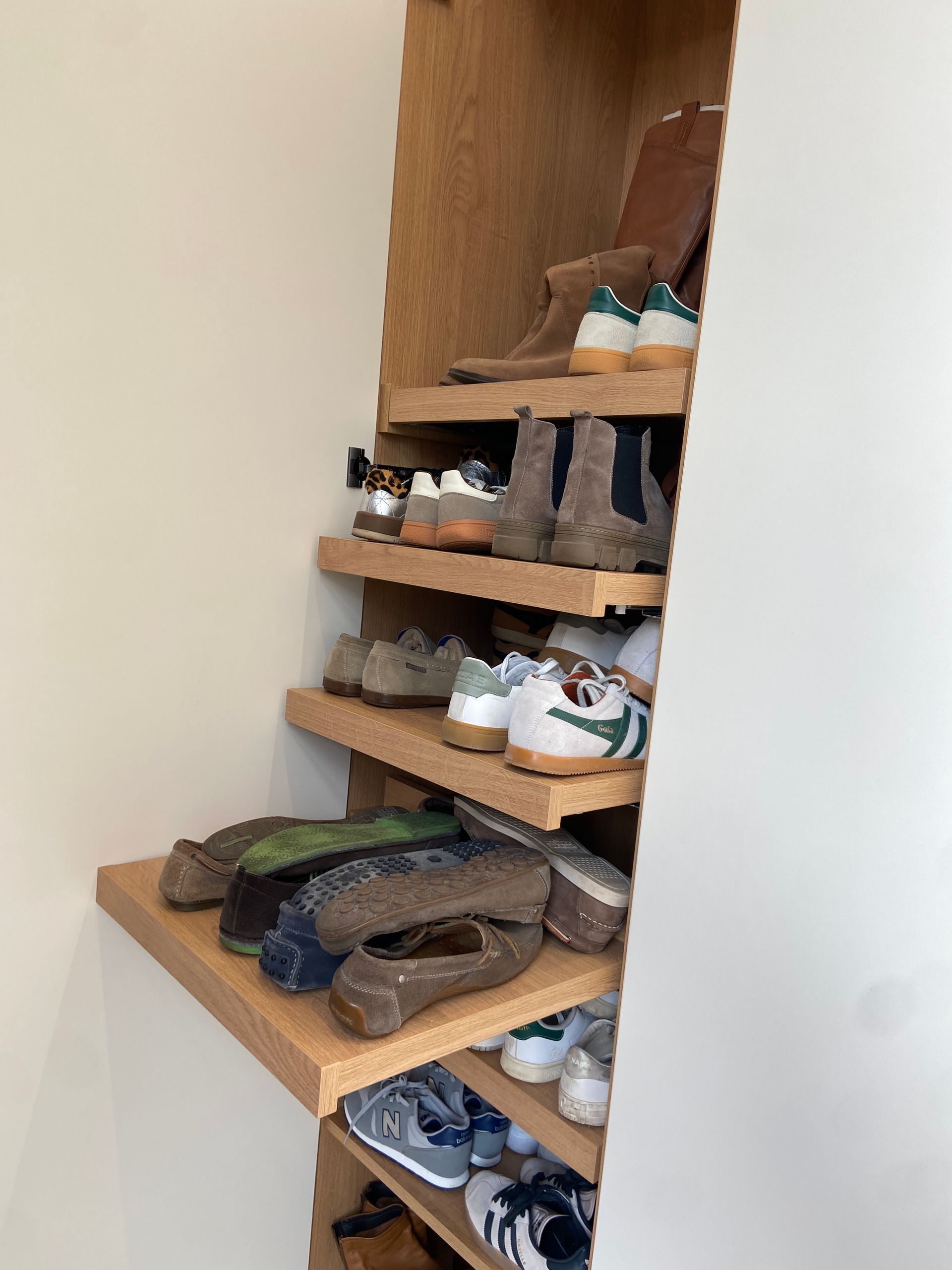 Vestiaire avec des étagères à chaussures en bois, remplies de chaussures de toutes sortes, se trouvent à l'intérieur d'un placard.